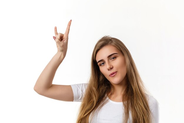 Mujer joven sonriente que muestra la mano del rock and roll