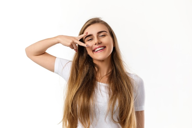 Mujer joven sonriente que muestra el signo de la victoria