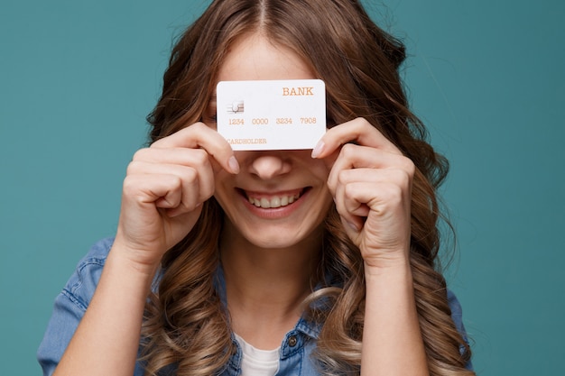 Mujer joven sonriente que sostiene la tarjeta de crédito del oro