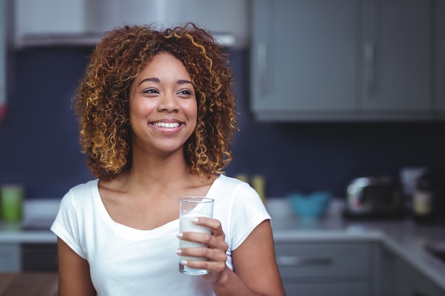 Mujer joven sonriente que sostiene el vaso de leche
