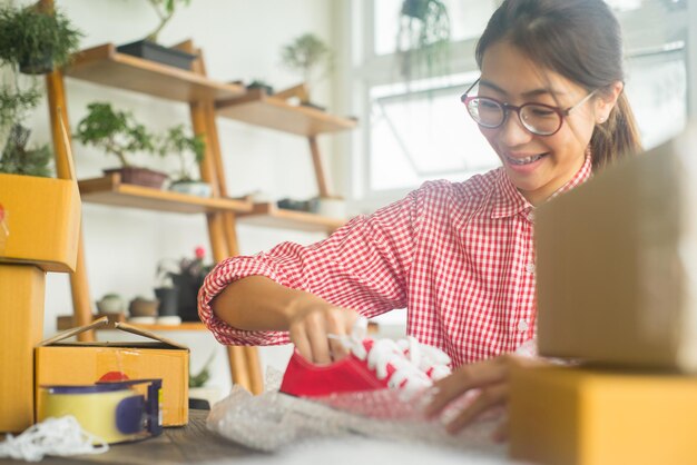 Foto mujer joven sonriente quitando zapatos del paquete en la mesa en casa