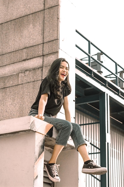 Mujer joven sonriente sentada en el edificio