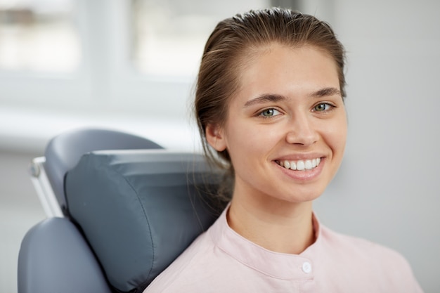 Mujer joven sonriente en silla dental