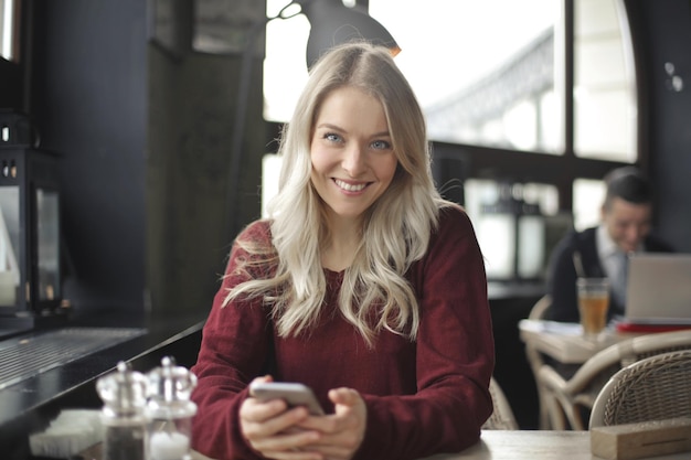 mujer joven sonriente con smartphone en un café