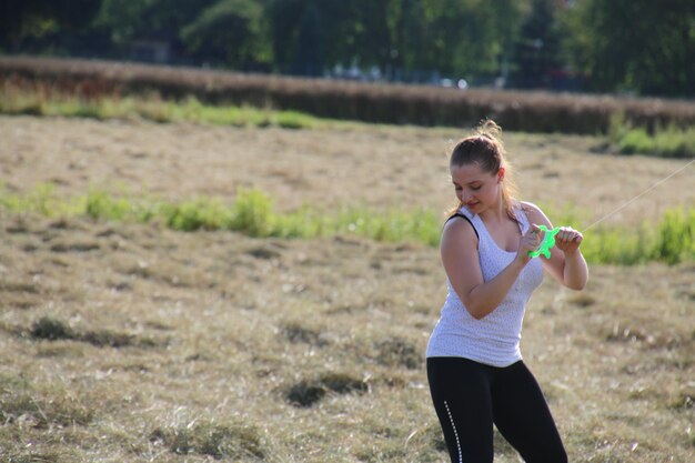 Mujer joven sonriente sosteniendo hilo en el campo
