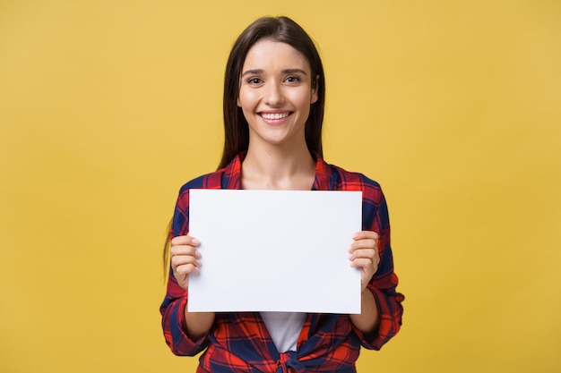Mujer joven sonriente sosteniendo una hoja de papel blanco Retrato de estudio sobre fondo amarillo