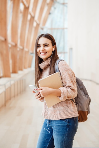 Mujer joven sonriente sosteniendo un libro mientras mira hacia otro lado