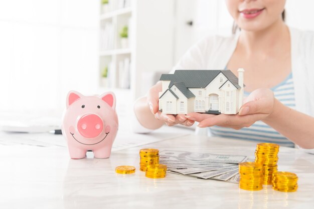 mujer joven sonriente sosteniendo un modelo de casa que muestra ahorrar dinero para comprar un nuevo concepto de apartamento. foto de enfoque selectivo.