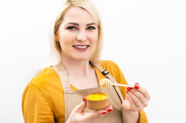 mujer joven sonriente con tazón de miel sobre fondo blanco