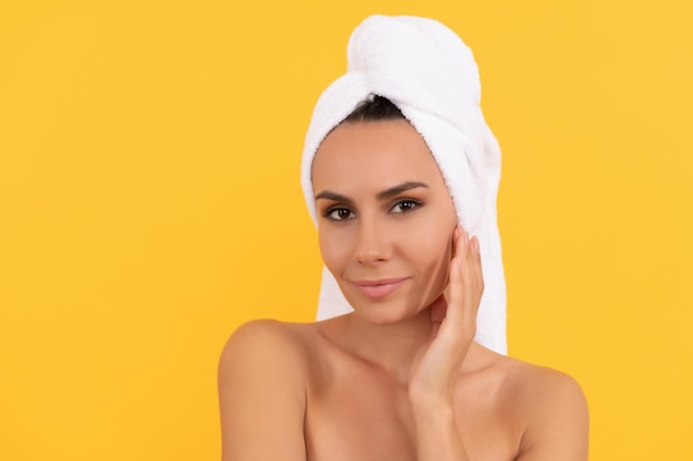 Mujer joven sonriente con toalla después de la ducha sobre fondo amarillo