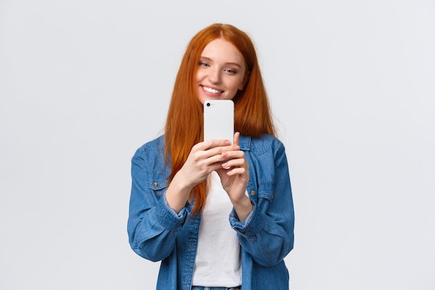 Mujer joven sonriente usando el teléfono contra un fondo blanco