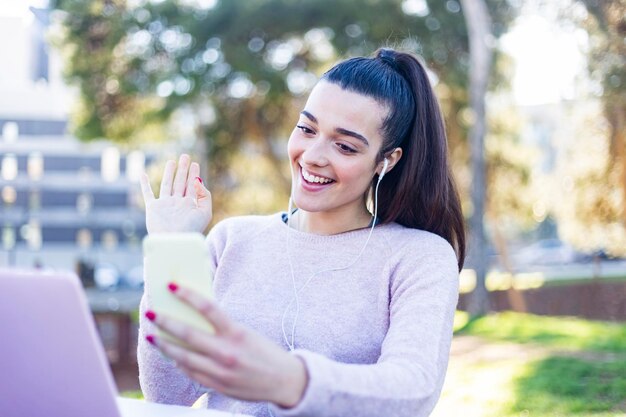 Foto mujer joven sonriente usando el teléfono móvil mientras está sentada al aire libre