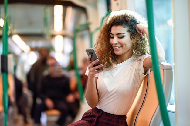 Foto mujer joven sonriente usando el teléfono móvil mientras está sentada en el vehículo