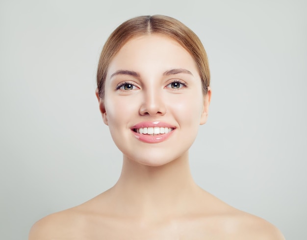 Mujer joven con una sonrisa perfecta Chica sonriente con piel clara sobre un fondo blanco Tratamiento facial y cuidado de la piel