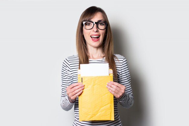 Mujer joven con una sonrisa saca una carta o aviso de un sobre de papel