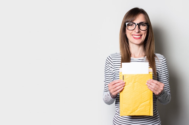 Mujer joven con una sonrisa saca una carta o aviso de un sobre de papel