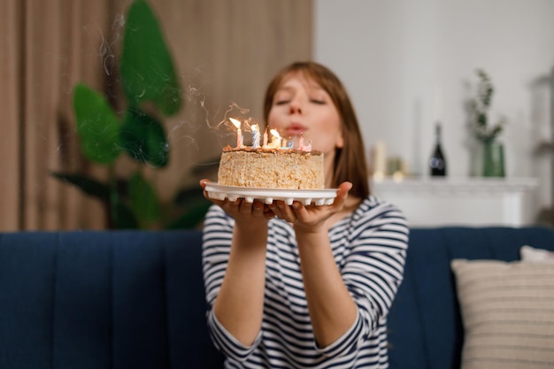 mujer joven, soplar velas, en, torta de cumpleaños