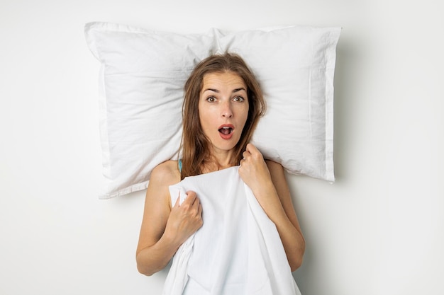 Foto mujer joven sorprendida acostada en una cama blanca vista superior plana