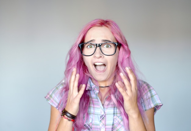 Mujer joven sorprendida con cabello rosado