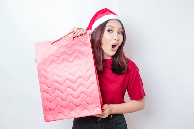 Foto una mujer joven sorprendida lleva un sombrero de santa claus39 y tiene regalos de navidad