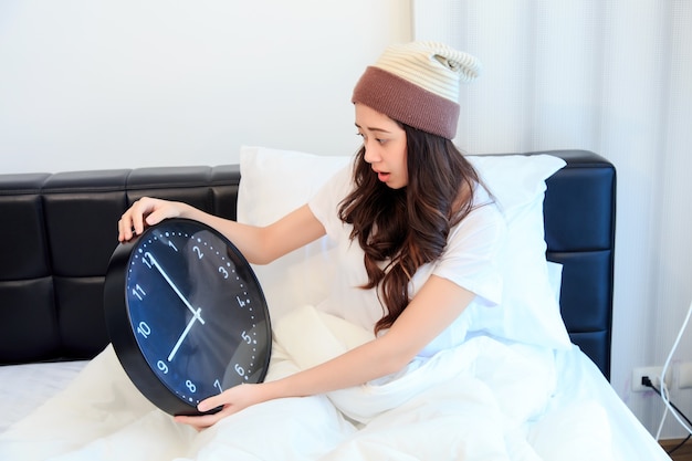 Mujer joven sorprendida que despierta con alarma en su dormitorio. concepto de salud y negocios