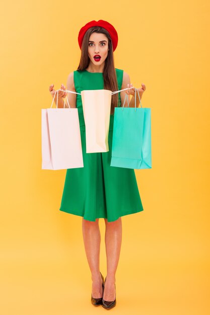 Mujer joven sorprendida que sostiene bolsos de compras