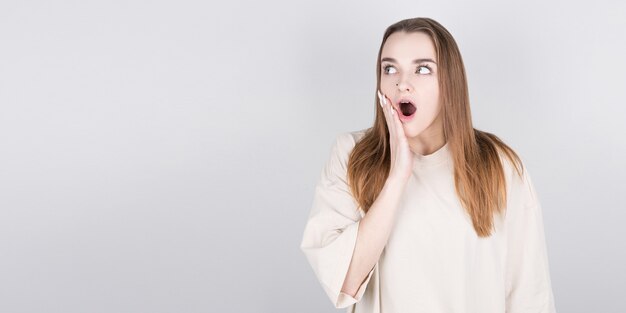 Mujer joven sorprendida sobre gris