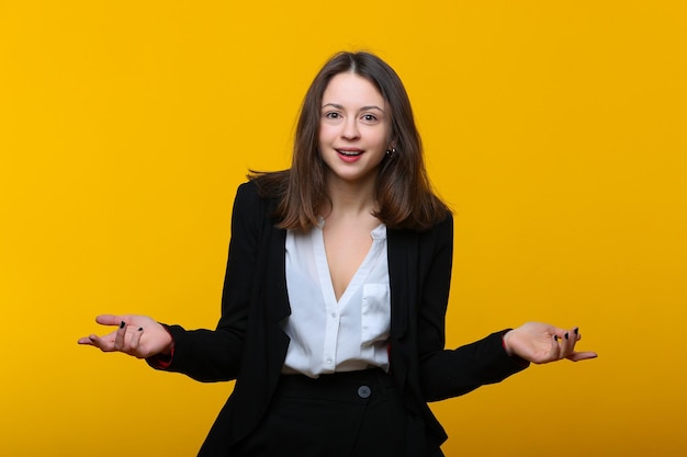 Mujer joven sorprendida en un traje de negocios sobre un fondo amarillo