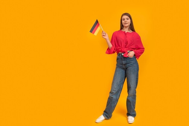 Mujer joven sosteniendo la bandera de Alemania Aprender alemán Colegiala de Alemania Programa de intercambio de estudiantes Fondo amarillo Espacio para texto