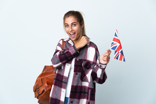 Mujer joven sosteniendo una bandera del Reino Unido aislada en la pared blanca celebrando una victoria