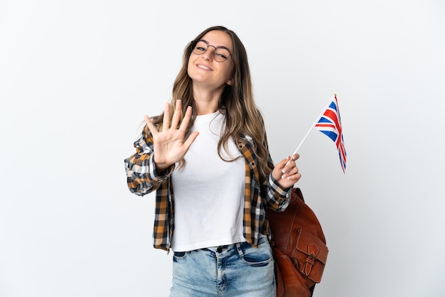 Mujer joven sosteniendo una bandera del Reino Unido posando aislado contra la pared en blanco