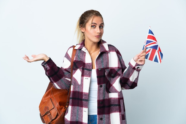 Mujer joven sosteniendo una bandera del Reino Unido posando aislado contra la pared en blanco