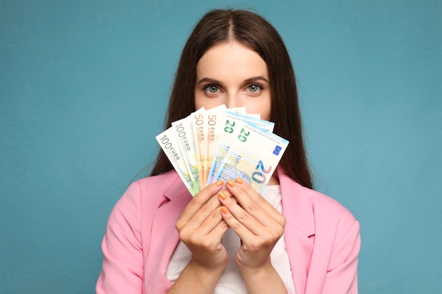 mujer joven sosteniendo billetes de euro cerca de su cara