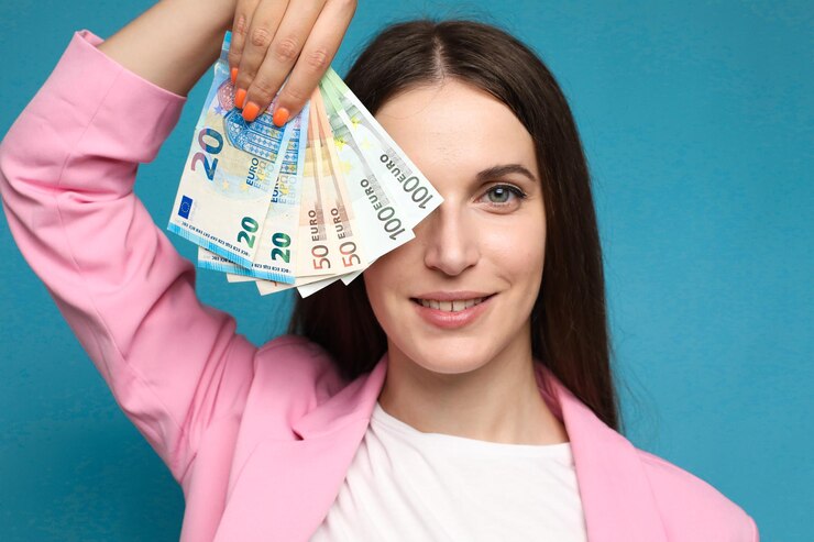 mujer joven sosteniendo billetes de euro cerca de su cara