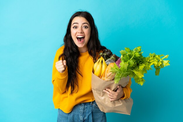 Mujer joven sosteniendo una bolsa de compras aislada