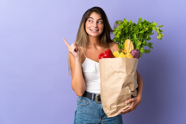 Mujer joven sosteniendo una bolsa de compras apuntando hacia una gran idea