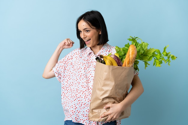 Mujer joven sosteniendo una bolsa de compras celebrando una victoria