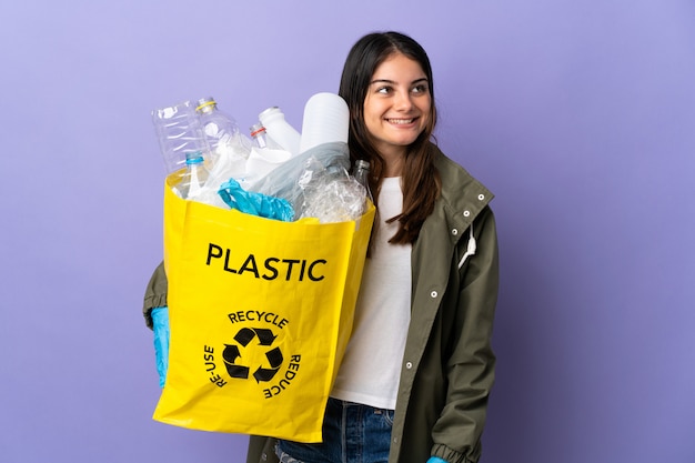 Mujer joven sosteniendo una bolsa llena de botellas de plástico para reciclar