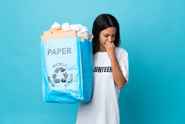 Mujer joven sosteniendo una bolsa de reciclaje llena de papel con dudas