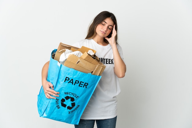 Mujer joven sosteniendo una bolsa de reciclaje llena de papel para reciclar aislado sobre fondo blanco con dolor de cabeza