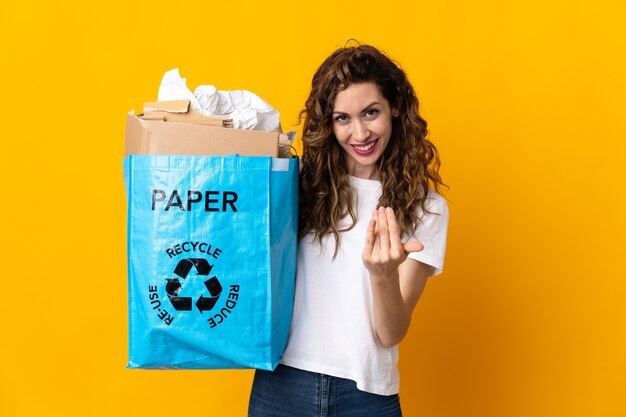 Mujer joven sosteniendo una bolsa de reciclaje llena de papel para reciclar