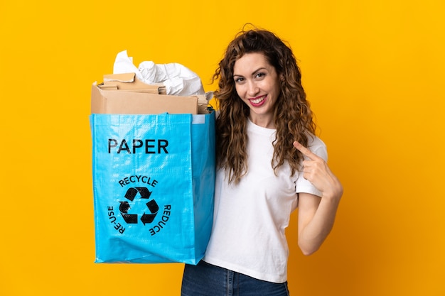 Mujer joven sosteniendo una bolsa de reciclaje llena de papel para reciclar