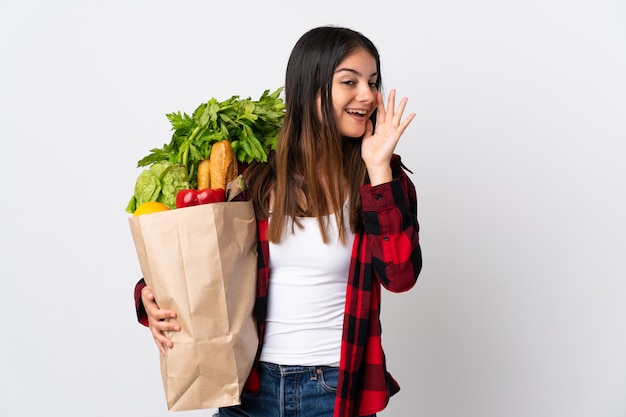 Mujer joven sosteniendo una bolsa con verduras