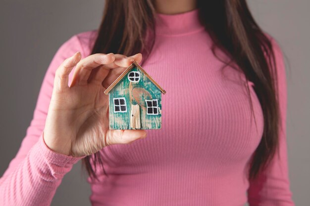 Mujer joven sosteniendo una casa en sus manos