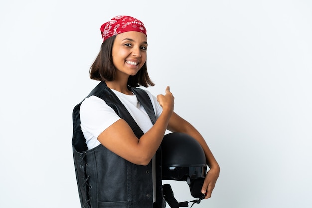 Mujer joven sosteniendo un casco de motocicleta aislado en blanco apuntando hacia atrás