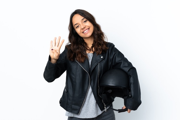 Mujer joven sosteniendo un casco de motocicleta sobre blanco aislado feliz y contando cuatro con los dedos