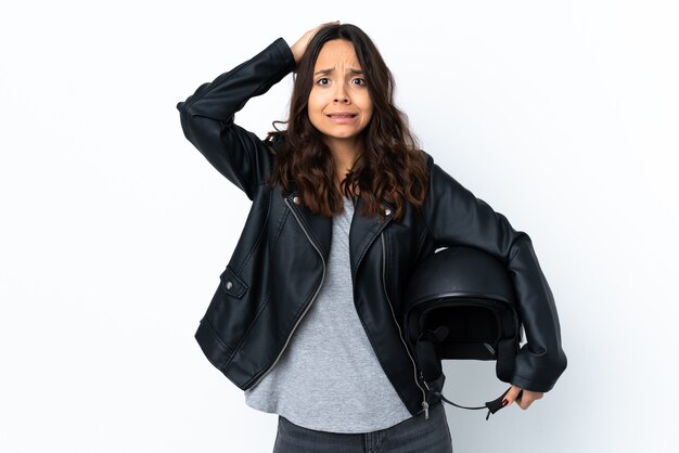 Mujer joven sosteniendo un casco de motocicleta sobre blanco aislado frustrado y toma las manos en la cabeza