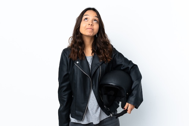 Mujer joven sosteniendo un casco de motocicleta sobre blanco aislado y mirando hacia arriba