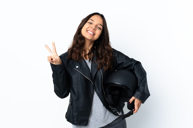 Mujer joven sosteniendo un casco de motocicleta sobre blanco aislado mostrando el signo de la victoria con ambas manos