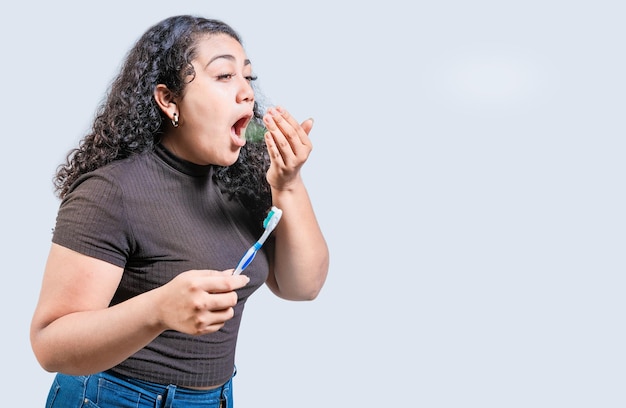 Mujer joven sosteniendo un cepillo con mal aliento aislada Persona con cepillo y mal aliento aislada Persona con halitosis